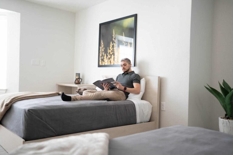 Man in bed reading book at Guardian Recovery Center in Dallas, Texas